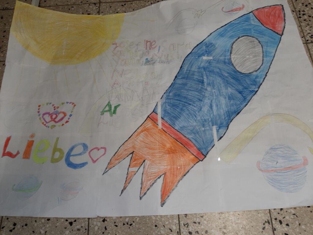 Foto eines gezeichneten Plakats mit einer blau-roten Rakete, einer Sonne , einem Planeten und dem Schriftzug Liebe.