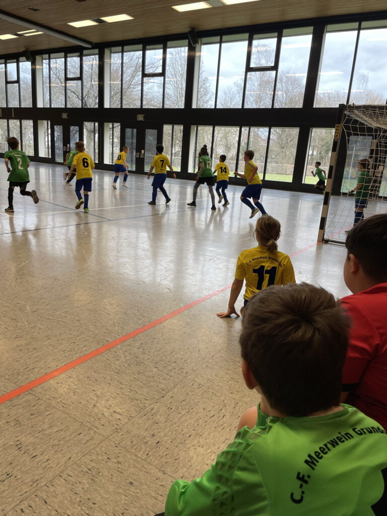 Foto eines Fussballspiels einer gelb-blau gekleideten Kindermannschaft gegen eine Mannschaft mit grünen Trikots